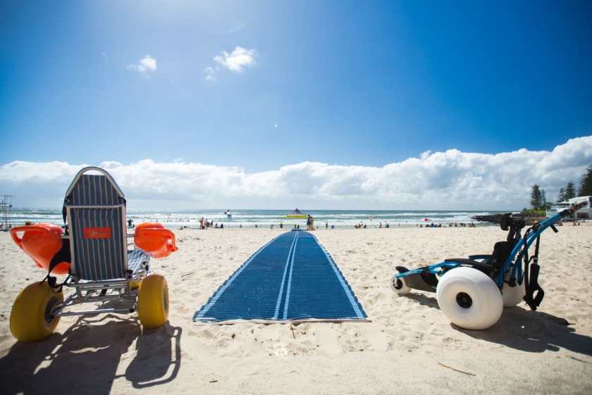 Two beach wheelchairs on Burleigh Beach with matting down to the water